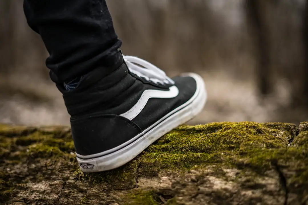 person wearing black and white Vans Sk8-Hi