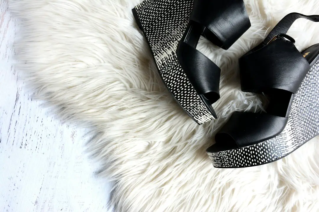 pair of women's black-and-gray wedges on white fur textile