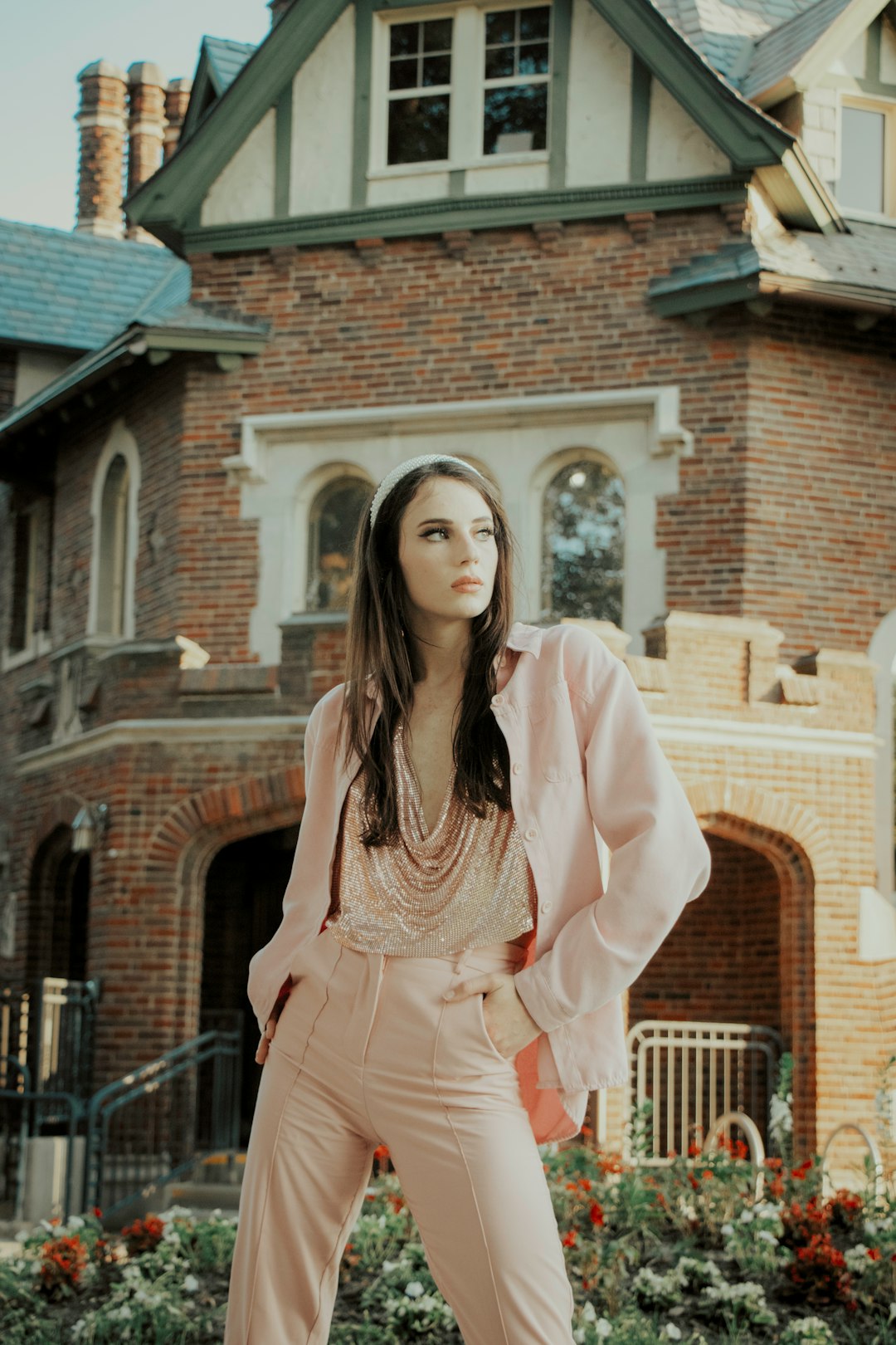 woman in pink long sleeve dress standing near brown brick building during daytime