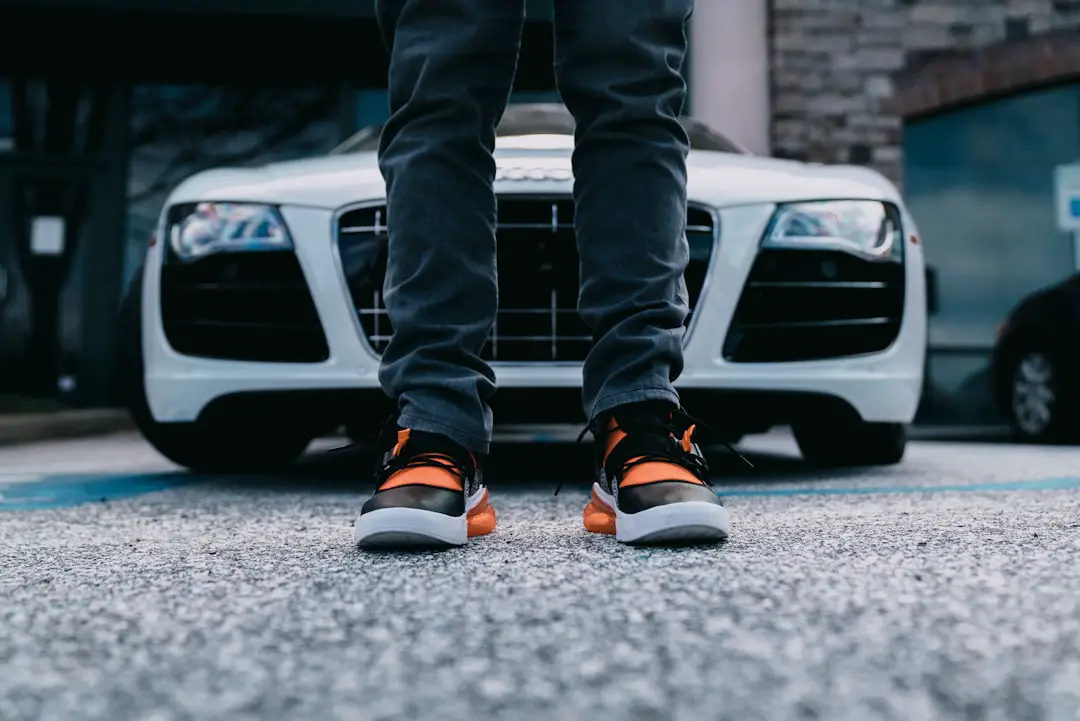 person wearing orange and black shoes behind white car