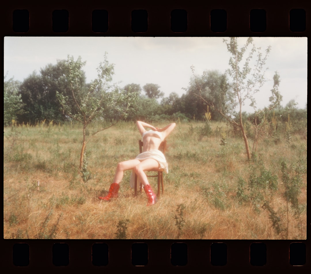 A woman sitting on top of a chair in a field