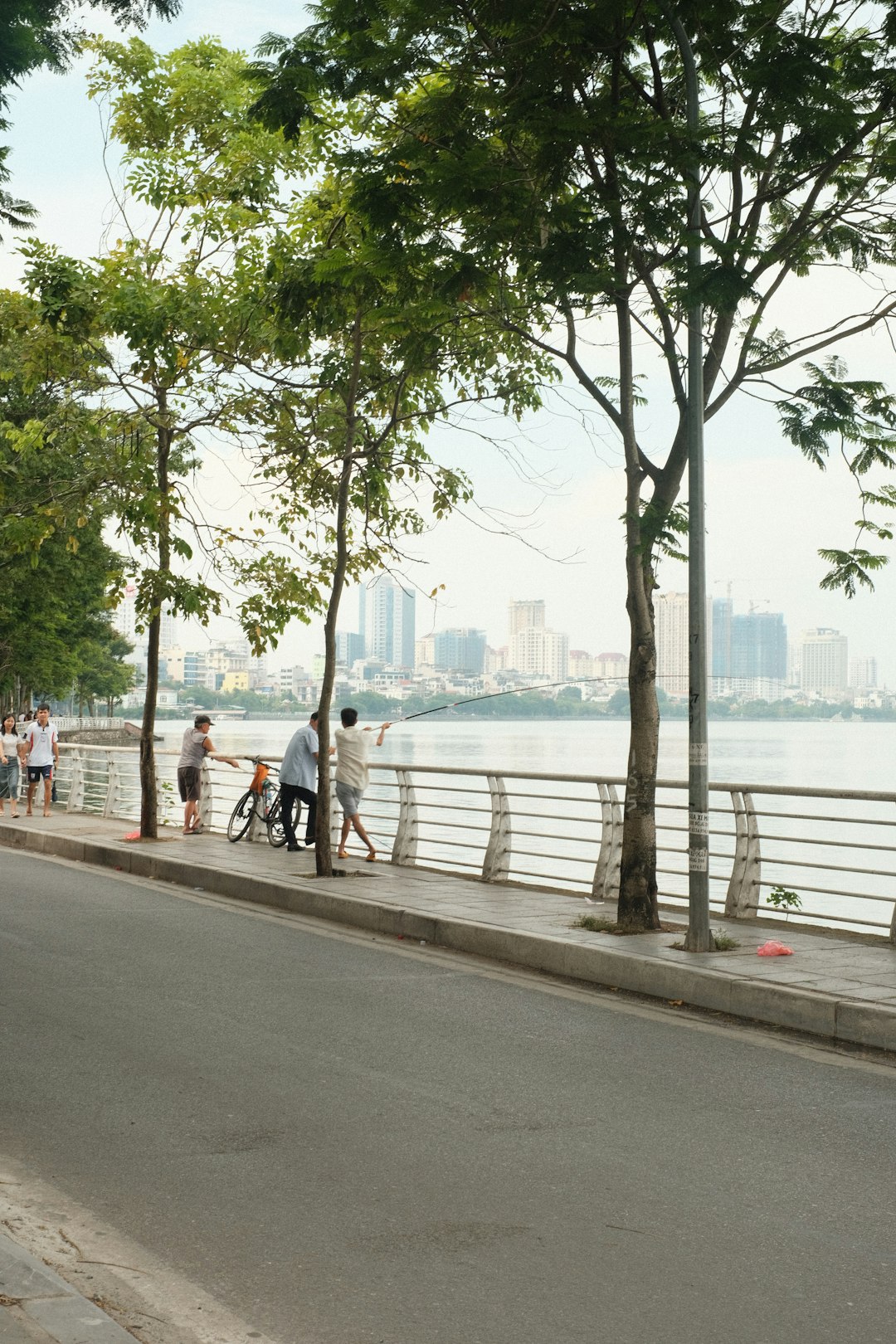 a group of people walking down a sidewalk next to a river