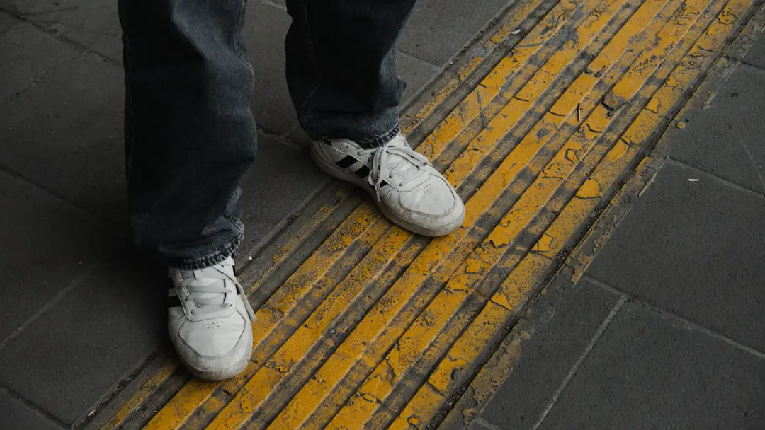 A person standing on a sidewalk with white shoes