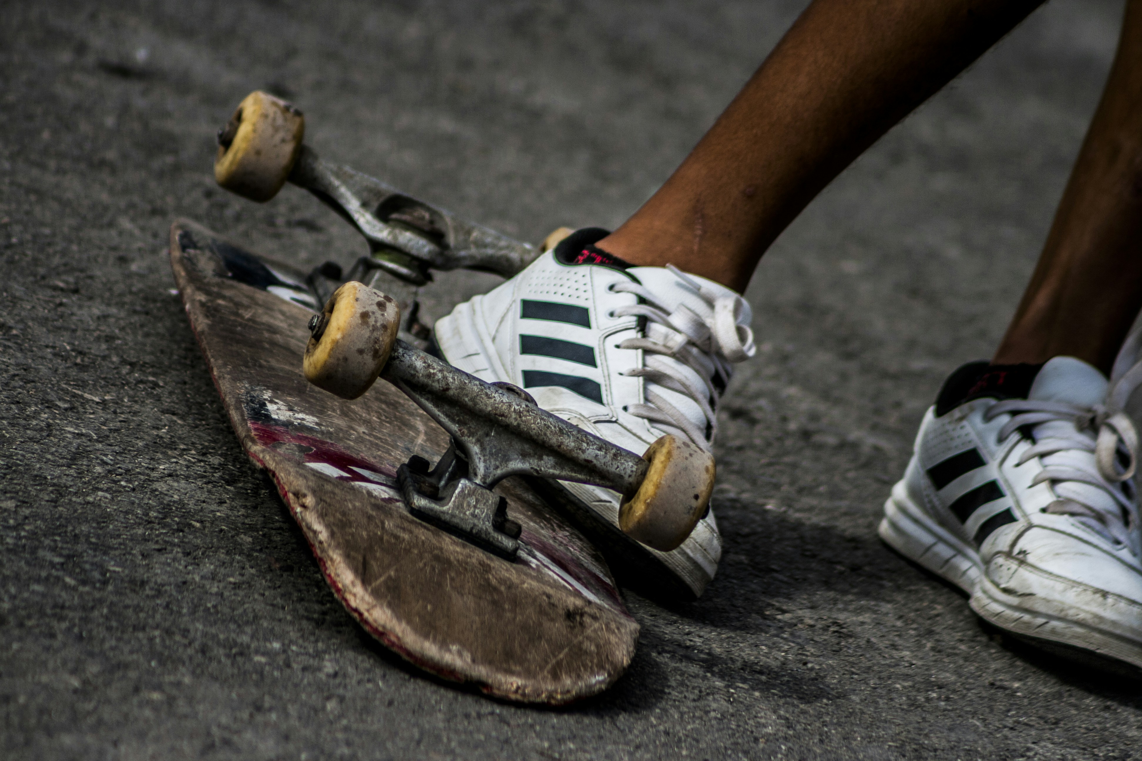 person wearing sneakers kicking skateboard during daytime